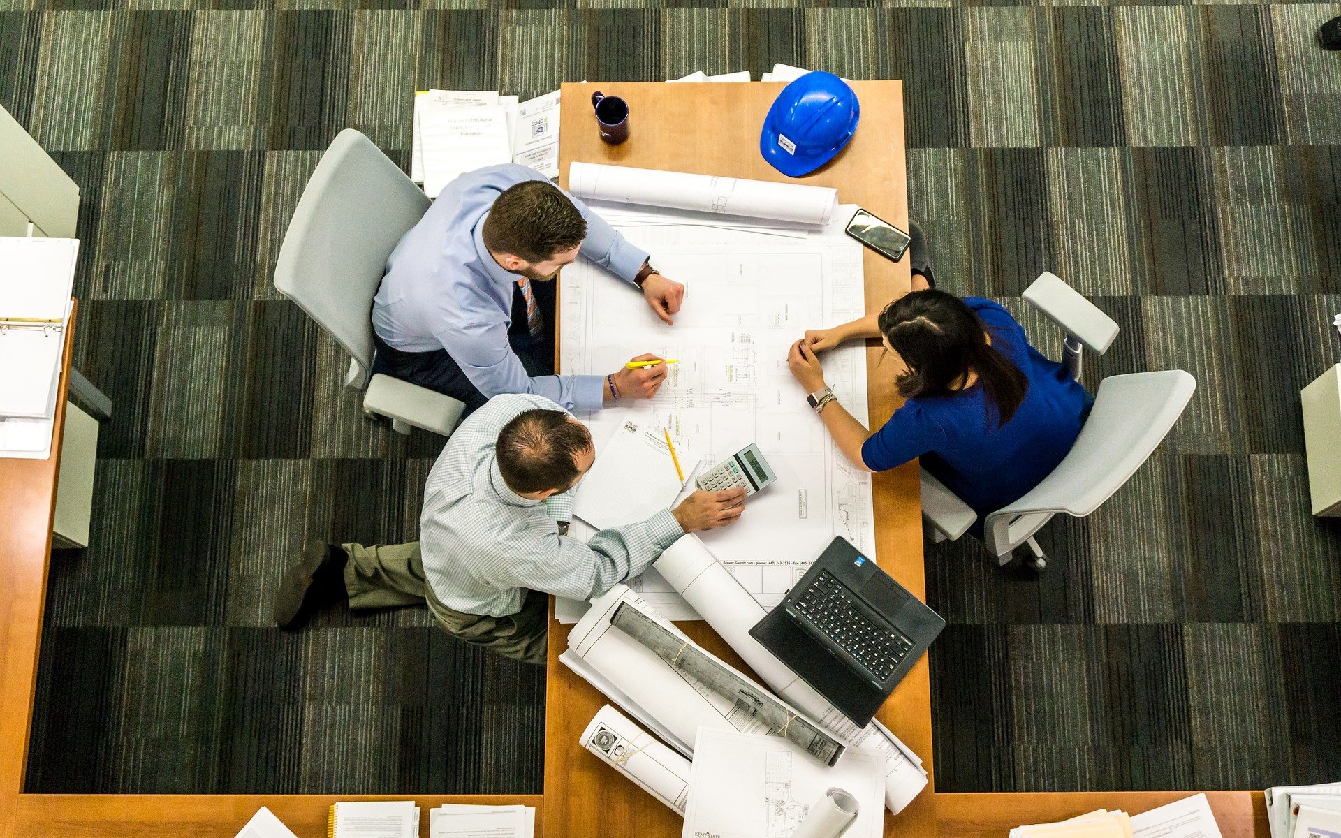 Bird’s eye view of people collaborating at a desk with a large drawing plan